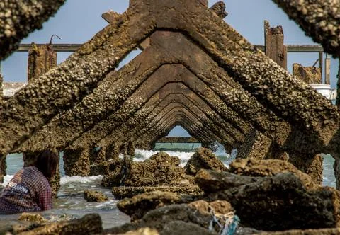Fishermen under at Broken old structure remains of pier in the sea. Stock Photos