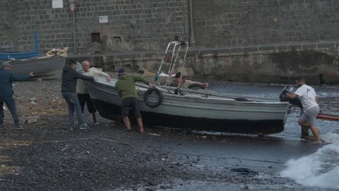Fishermen working as a team push a boat on the shore Stock Footage 102436279