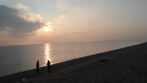 Fishers start their day in a quiet beach with a pink sunrise Stock Footage 98700142