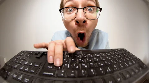 Fisheye portrait of crazy nerd with glasses typing keyboard, looking at camera Stock-Footage 167277444