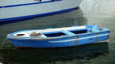 An fishing boat with cracked blue paint floating on clear sea water. Greece. 4K Stock Footage 122671453