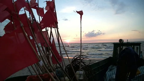 Fishing boat with red flags on the beach during sunset 動画素材 121683247