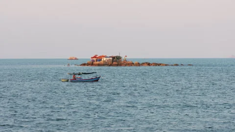 Fishing boat sailing near a tiny rocky island Stock Footage 336564880