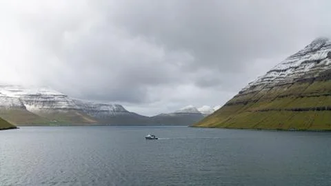 Fishing boat sailing through dramatic landscape on Faroe Islands Stock-Fotos