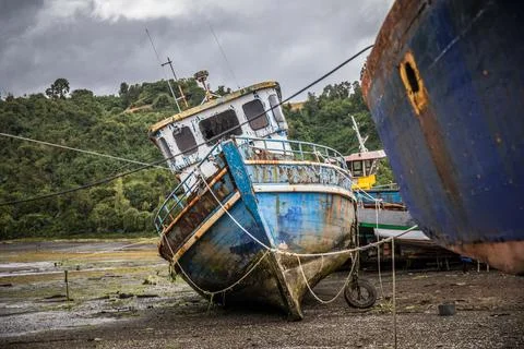 A fishing boat is stranded ashore in a small harbor on Chiloe during low ti.. Stock Photos