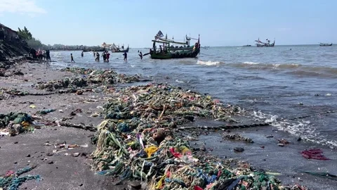 Fishing boats arriving at a beach, full of garbage, sunny day in Java, Stock Footage 252184896