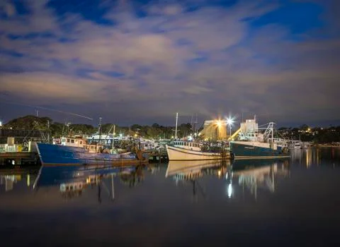 Fishing boats at dock on still waters Stock Photos