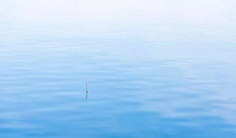 Fishing cork float on calm blue water perspective peaceful surface background Stock Photos
