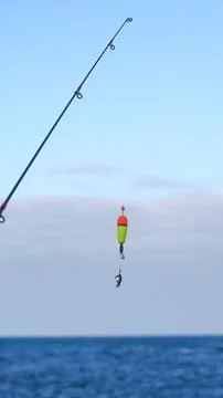 Fishing Float and Small Crab Hanging from Hook Over Calm Water Stock Photos
