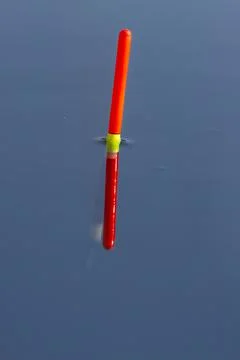 The fishing float sits upright in the smooth blue water Stock Photos