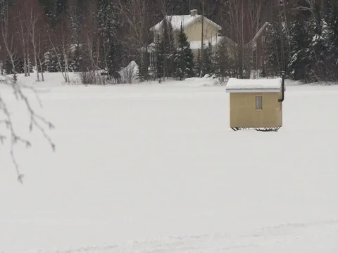 A fishing hut in the framed right of the camera and a house in the background Video stock 79691138