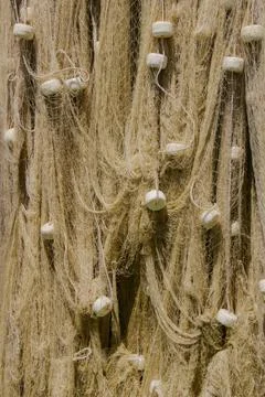 Fishing net displayed under sunlight at a coastal location with intricate d.. Stock Photos