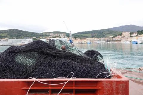 A fishing net is placed in a red container at the water's edge, with a view o Stock Photos
