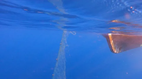 Fishing net is pulled underwater toward a boat - Mesh Texture and Water Current Stock Footage 340007113