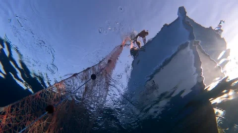Fishing net is pulled underwater toward a boat through blue water - Sandy Bottom Stock Footage 340007799