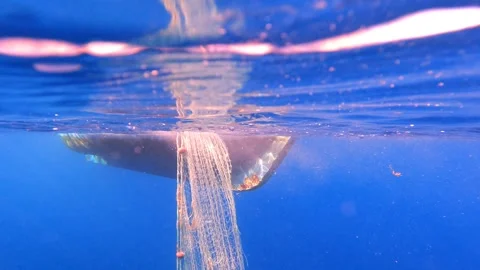 Fishing net rises underwater toward boat hull as catch gear is pulled - Workboat Stock Footage 339975758