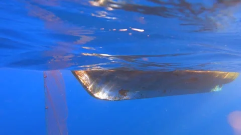 Fishing net rises underwater toward boat hull as catch gear - Fishing Process Stock Footage 339975838