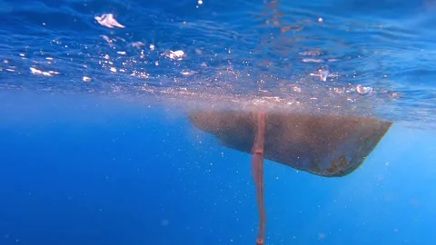Fishing net rises underwater toward boat hull - Workboat and Fishing Process Stock Footage 339975927