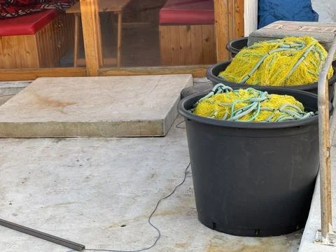 Fishing nets in large black containers on dockside with wooden cabin in bac.. 库存照片