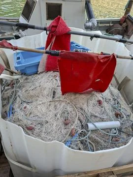 Fishing nets with red marker flags stored in a plastic tub on a boat deck d.. Stock Photos