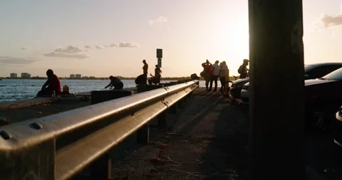 Fishing pier at sunset. Silhouettes of multiple people. 4K footage. Stock Footage 154423937