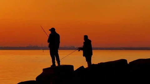 Fishing off rocks at sunset on the ocean 스톡 동영상 259021146