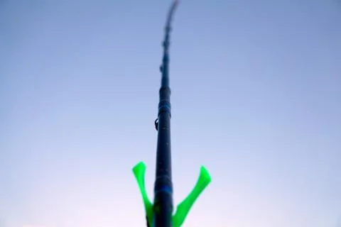 The fishing rod with a bite indicator on the stand on the lake . Stock Photos