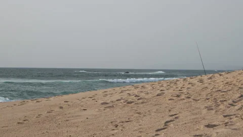 Fishing rod standing on empty beach with ocean in background Stock Footage 172484938