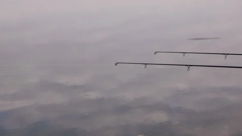 Fishing rods over calm reflective water on cloudy autumn day, minimalist Stock Footage 319662463