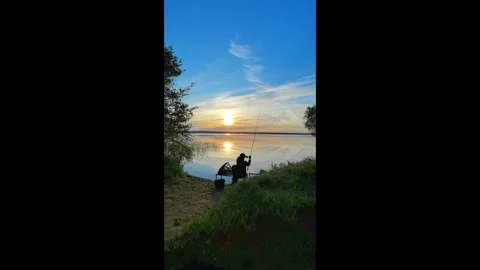 Fishing at sunset by the lake while sitting on the shore and enjoying the quiet Stock Footage 335945833
