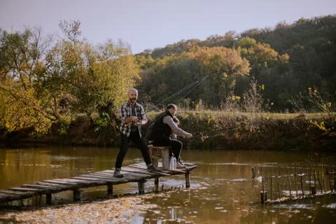 Fishing time for two guy and one cute small boy in the middle of nature beside a Stock Photos
