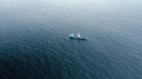 A fishing vessel equipped with a trawl catches fish in the open ocean. Stock Footage 133669341