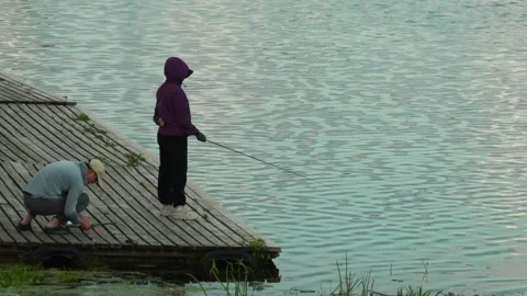 Fishing by the water at a lakeside dock during the evening Vidéo 340447962