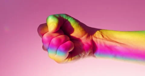 Fist Gesture in Rainbow Light over Pink Background in slow motion Stock Footage 347957638