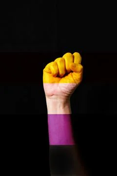 Fist hand with non-binary pride flag patterned isolate on black. LGBTQ+ right Stock Photos