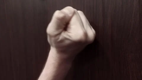 Fist knocks on front door. Close up shot man fist knocking on front wooden door Stock Footage 344094311