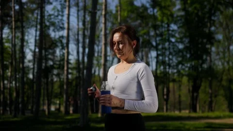 Fit 45 year old woman opening water bottle during outdoor fitness 库存影片 335191253