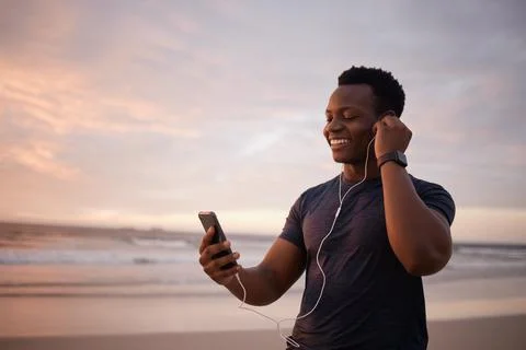 Fit african american man using earphones to listen to music through cellphone Stock Photos