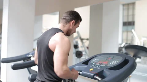 Fit athletic man is starting to run on the treadmill in the sport gym Stock Footage 62561867
