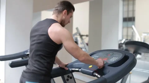 Fit athletic man is starting to run on the treadmill in the sport gym Stock Footage 62561877