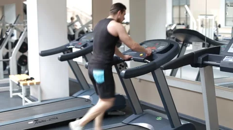 Fit athletic man is starting to run on the treadmill in the sport gym Stock Footage 62561894