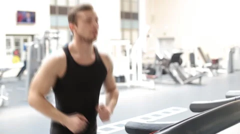Fit athletic man is starting to run on the treadmill in the sport gym Stock Footage 62561907