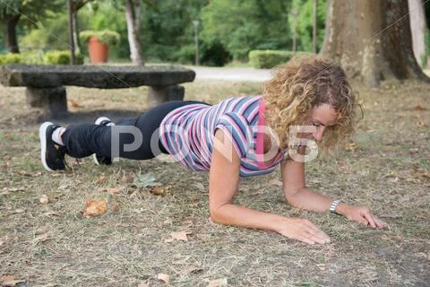 Fit blonde senior in plank position park on a sunny day Stock Photos