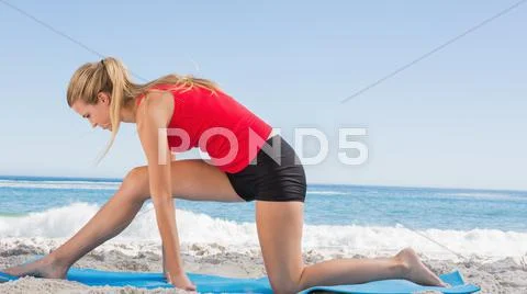Fit blonde stretching leg on exercise mat Stock Photos