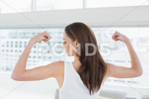 Fit brown haired woman flexing muscles in fitness studio Stock Photos