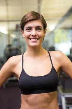 Fit brunette in black sports bra smiling at camera Stock Photos
