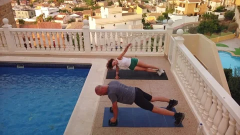 Fit Couple Doing Push Ups with Handles and Side Plank Arm Reaches Poolside Stock-Footage 345385991