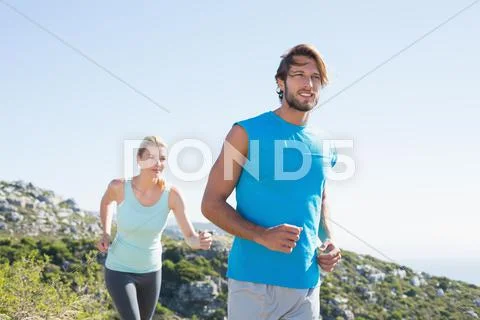 Fit couple jogging through countryside Stock Photos