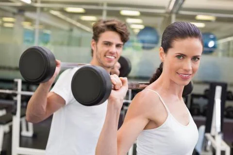 Fit couple lifting barbells together Stock Photos