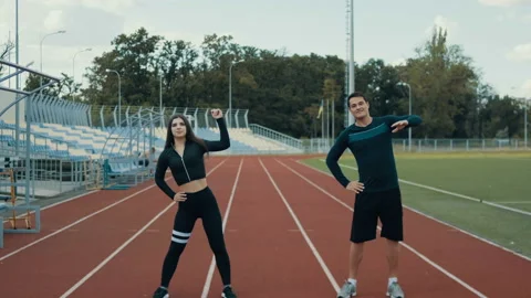 Fit couple training together on athletics. Athlete man and woman warm up before Stock Footage 125395553